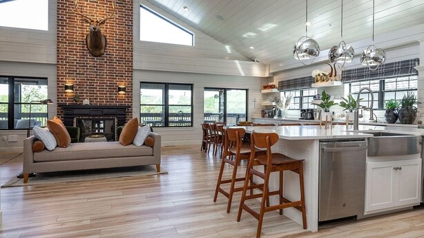 Una cocina amplia con una isla grande, sillas de madera y una chimenea de ladrillo.