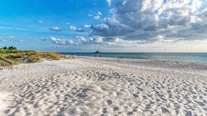 A sandy beach with a gazebo and a clear view of the sea.