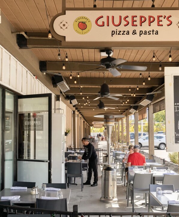 Giuseppe's Pizza & Pasta dispose d'un espace extérieur aménagé avec des tables et des chaises, des ventilateurs de plafond et des lampes suspendues.