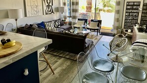 A modern living room with a sofa, chairs, a dining area, and artwork on the walls. - Smoke Tree Racquet Club Condo 7 min Drive to Downtown Palm Springs!  (Palm Springs)