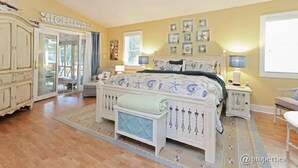 A bedroom with a bed, bedside tables, a wardrobe, and a window. - Charming New Buffalo Cottage (New Buffalo)