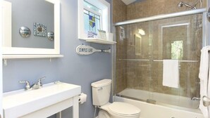 A bathroom with a glass-enclosed shower, a white sink, and a toilet. - Charming New Buffalo Cottage (New Buffalo)