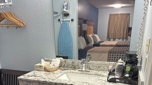 A bathroom with a marble sink, a mirror, a towel rack, a trash bin, and a coffee maker. - Tanglewood Motel (Frederick)