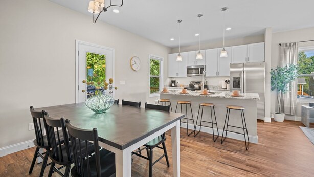A modern kitchen with a central island, bar stools, and pendant lighting.