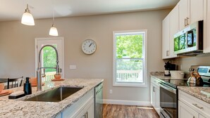 A kitchen with granite countertops, white cabinets, a stainless steel sink, and a built-in oven.