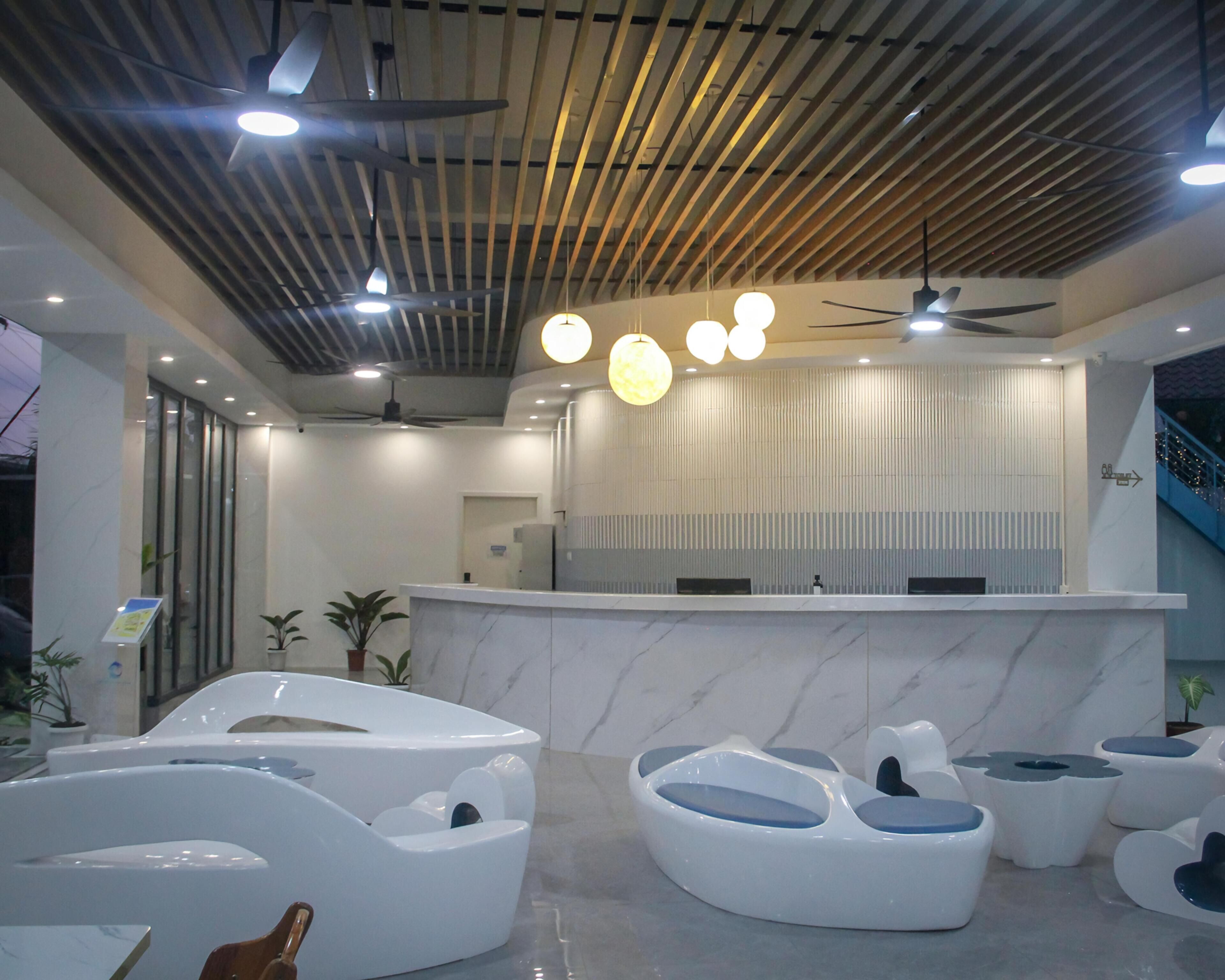 A modern reception area with a marble reception desk, ceiling fans, and unique white and blue seating arrangements.