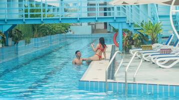 A swimming pool area with a blue and white building in the background.