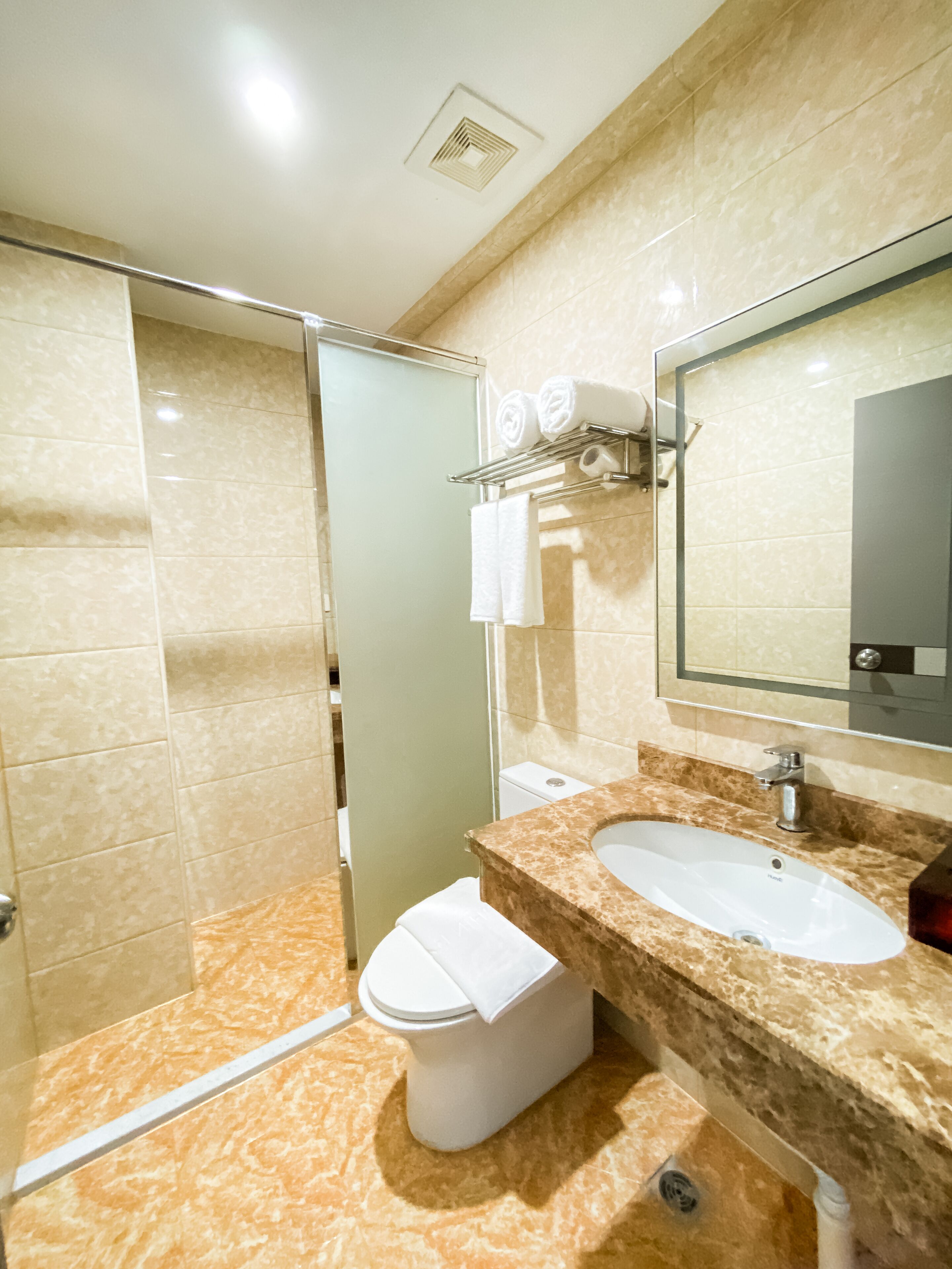 A modern bathroom with a glass shower enclosure, a sink with a marble countertop, and a toilet.