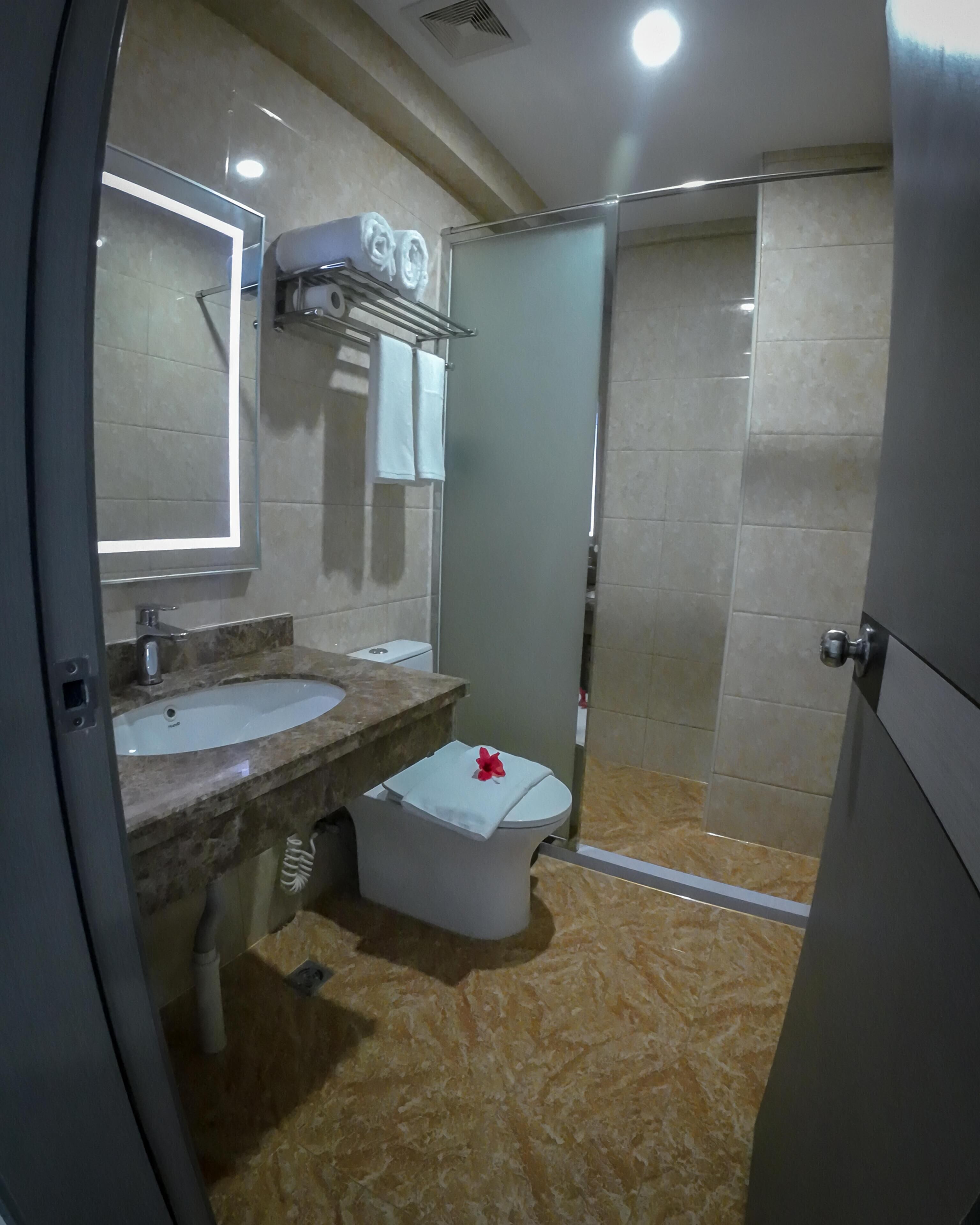 A modern bathroom with a marble sink, a mirror, and a shower area.