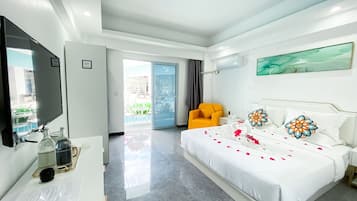 Habitación de hotel moderna con una cama grande, un televisor de pantalla plana, un escritorio con ordenador y un balcón con vistas a la piscina.