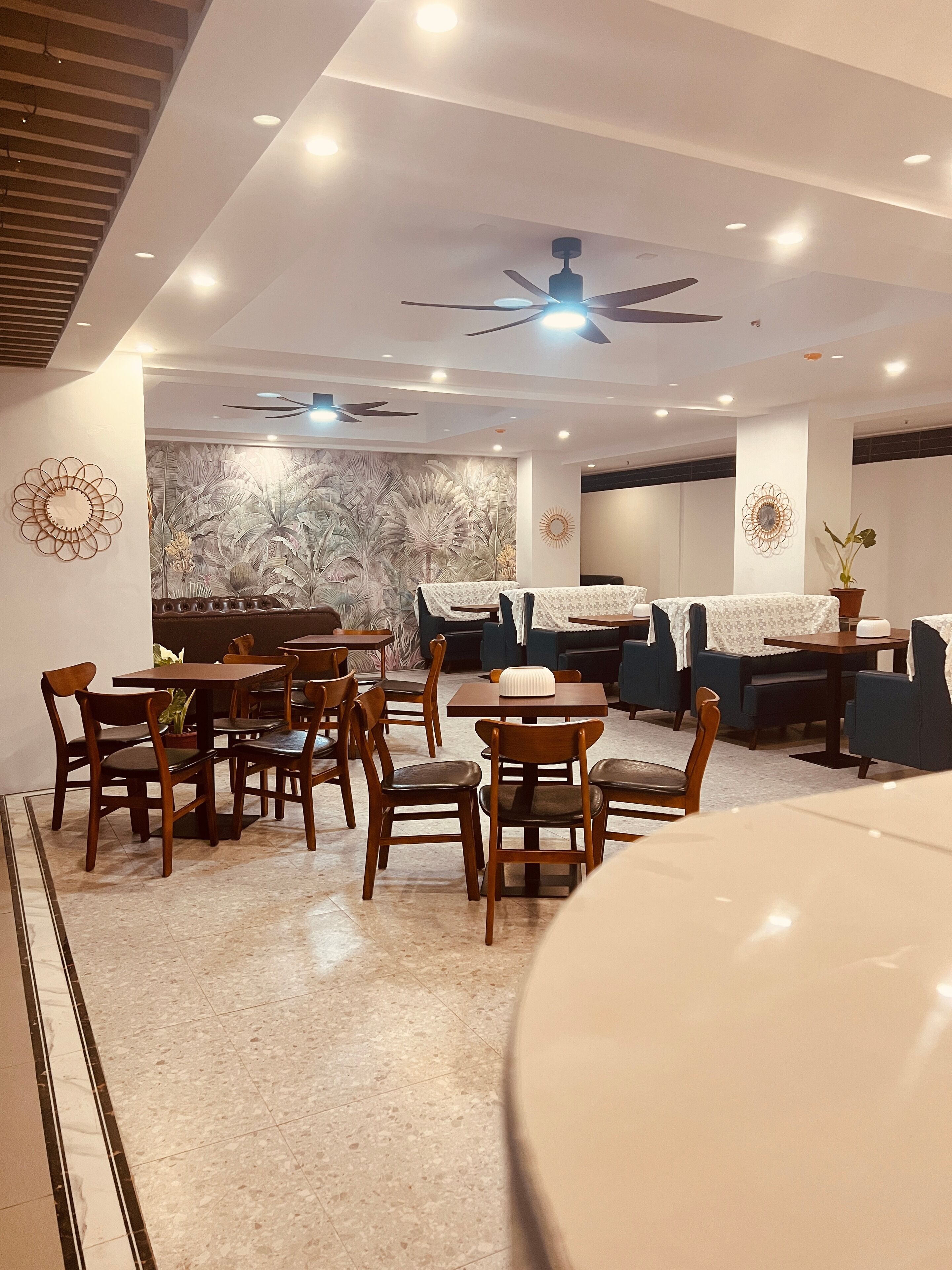 A modern dining area with wooden furniture, a ceiling fan, and a decorative wall mural.