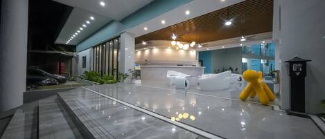 A modern lobby with a marble floor, a reception desk, and a yellow sculpture.