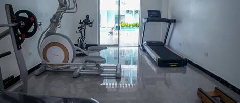 A modern gym with a variety of equipment including a stationary bike, elliptical, treadmill, and weight bench.