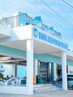 Exterior del complejo turístico Bohol Dolphin Bay Resort, con un llamativo logotipo de delfín y un diseño arquitectónico moderno.