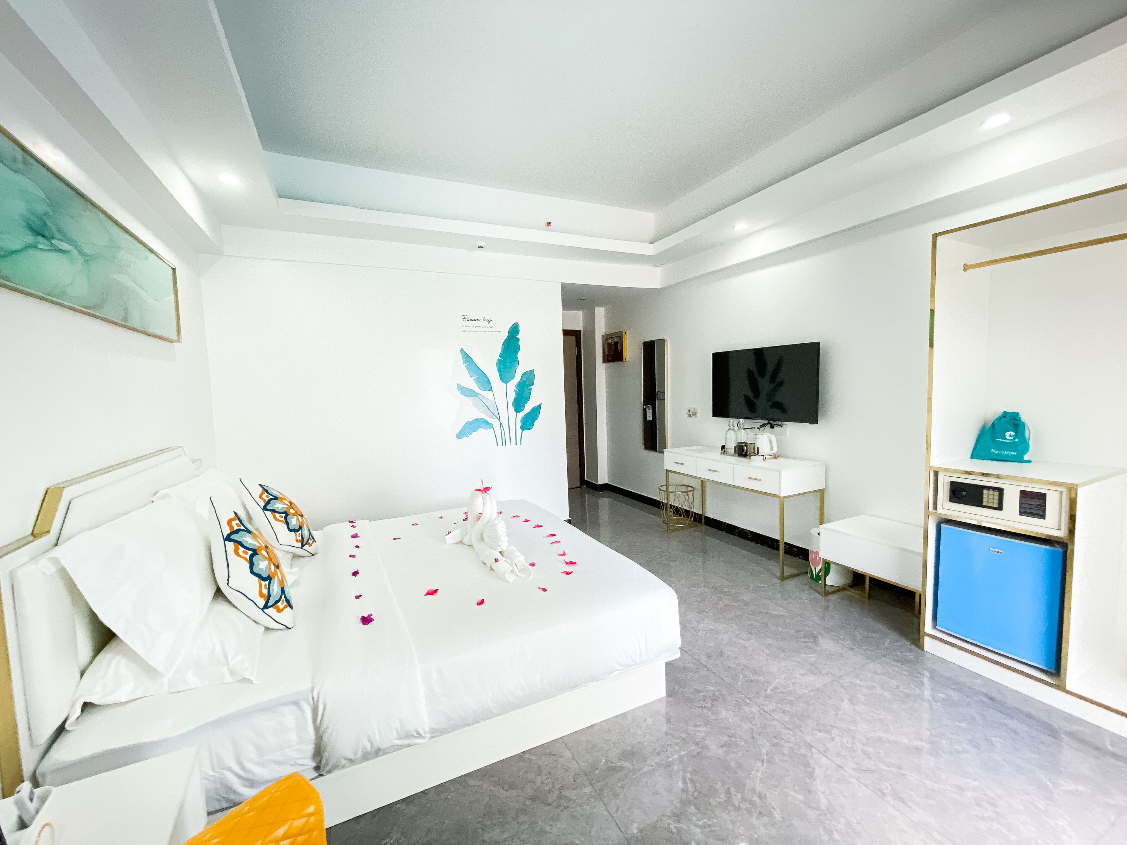 A hotel room with a bed, a desk, a TV, and a minibar.