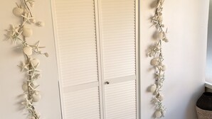 Um armário branco com uma placa 'Laundry' em cima, ladeado por guirlandas decorativas com conchas e estrelas-do-mar.