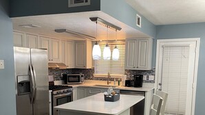 A modern kitchen with a central island, stainless steel appliances, and pendant lighting. - Siren’s Call, with only a 4 min walk to the beach, is truly irresistible!  (Panama City Beach)
