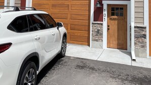 A two-story house with a red exterior, a white garage door, and a white SUV parked in front.
