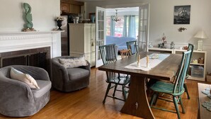 A dining area with a wooden table, green chairs, and a fireplace. - Classic Cape Steps from the Beach (Barnstable)