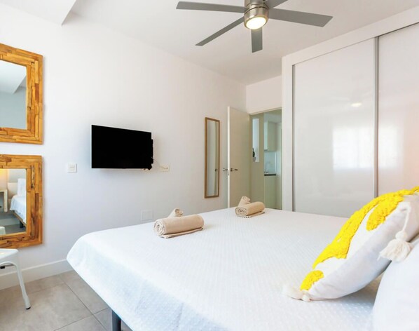 Ein Hotelzimmer mit Bett, Deckenventilator, Flachbildfernseher und Spiegel.