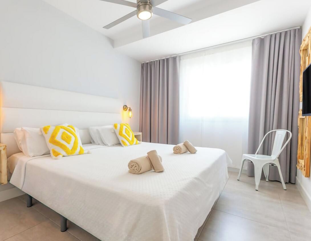 A hotel room with a large bed, a ceiling fan, a TV, and a chair.