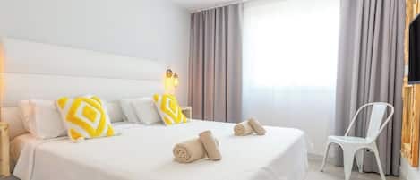 A hotel room with a large bed, a ceiling fan, a TV, and a chair.