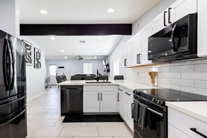 Une cuisine moderne dotée d’appareils électroménagers en acier inoxydable, de meubles blancs et d’un îlot central.