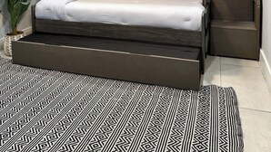 Un lit superposé avec un bureau intégré, un ventilateur de plafond et un tapis à motifs.