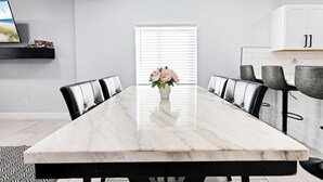 Une salle à manger moderne avec une table en marbre, des chaises noires et un vase de fleurs.