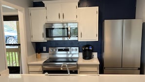 A modern kitchen with white cabinets, stainless steel appliances, and a blue accent wall. - Updated condo, Walk to Beech Mountain Resort, Beautiful sunrise, Pet friendly (Beech Mountain)