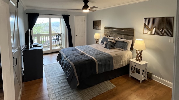 A bedroom with a bed, bedside lamps, a ceiling fan, a view through a glass door, and a small desk with a chair. - Updated condo, Walk to Beech Mountain Resort, Beautiful sunrise, Pet friendly (Beech Mountain)