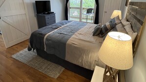 A bedroom with a bed, a TV, a ceiling fan, a window with curtains, and a door. - Updated condo, Walk to Beech Mountain Resort, Beautiful sunrise, Pet friendly (Beech Mountain)