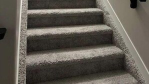 A carpeted staircase with a black handrail and a metal railing at the top.