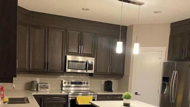 A modern kitchen with dark wood cabinets, stainless steel appliances, and a central island.