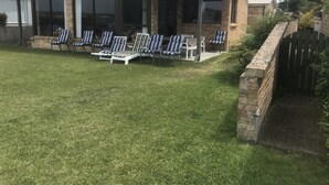A covered patio with outdoor seating and a brick wall. - 3 Bedroom house, right on the river, own private jetty (Greenwell Point)