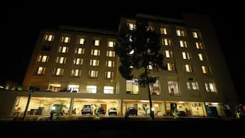 A multi-story hotel with illuminated windows and a parking area.