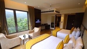 Habitación de hotel con dos camas, un sofá, un televisor y vistas al exterior.