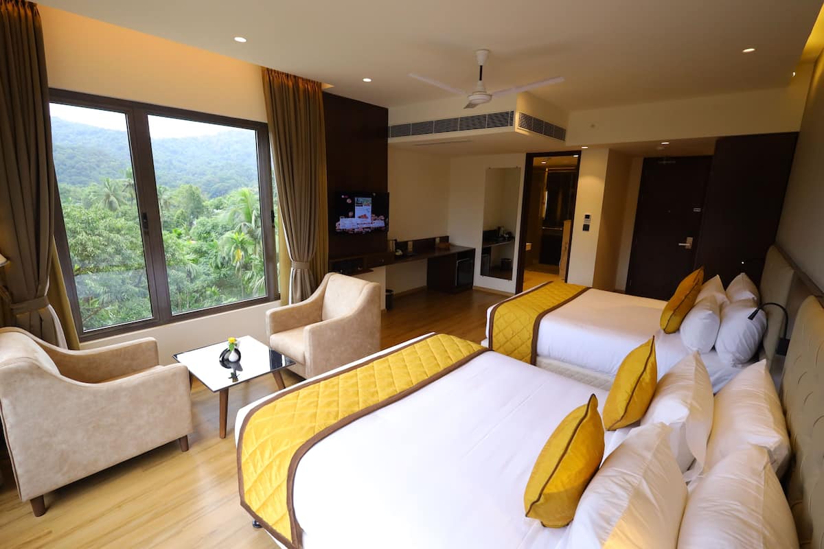 A hotel room with two beds, a sofa, a TV, and a view of the outdoors.