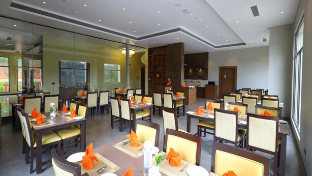 Comedor con varias mesas dispuestas para los huéspedes, área de cocina y mostrador de recepción.