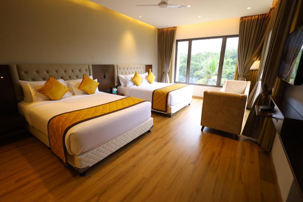 A hotel room with two beds, a chair, and a large window.