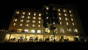 Un hotel de varios pisos con ventanas iluminadas y un estacionamiento al frente.