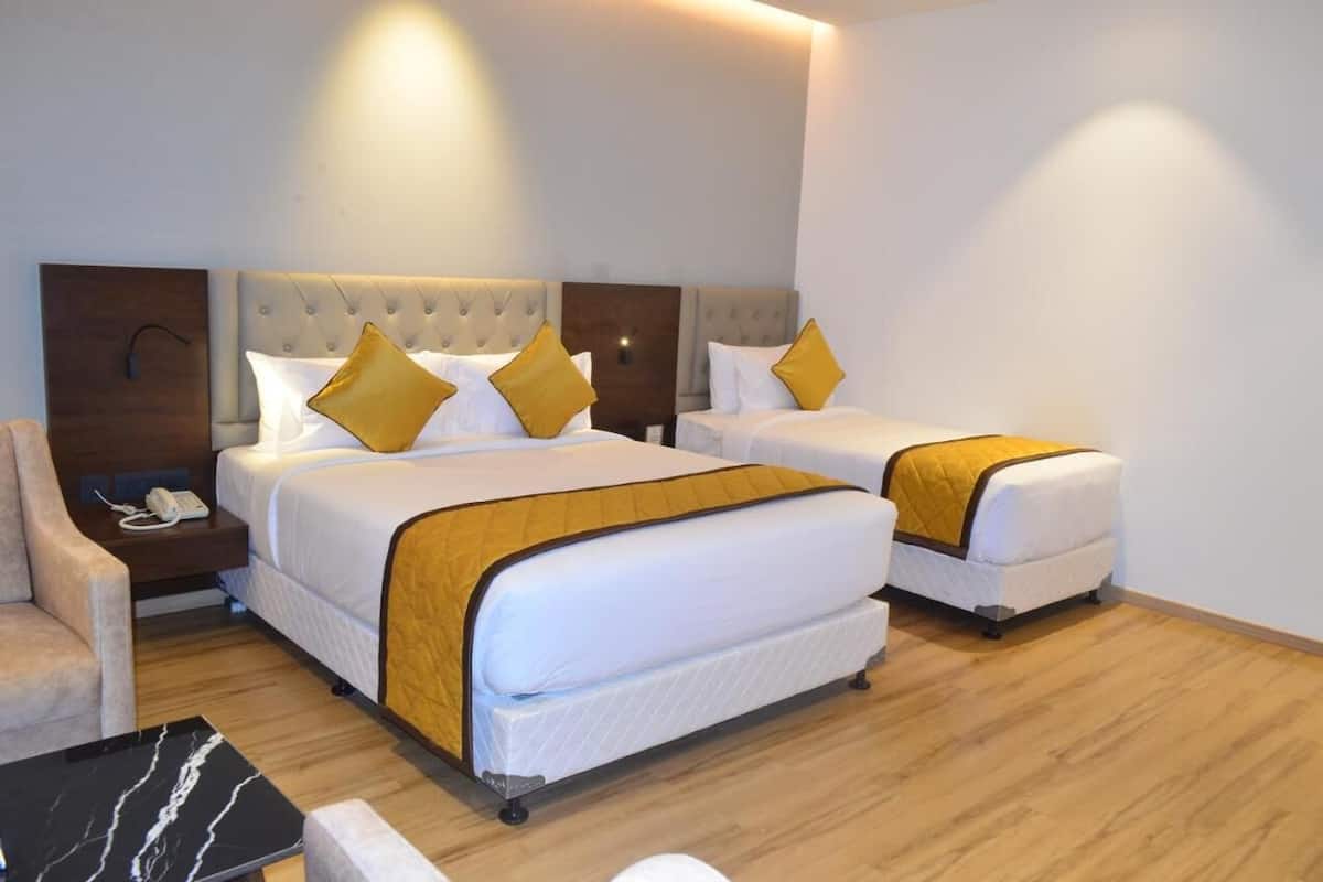 A hotel room with two beds, a nightstand, a chair, and a marble table.