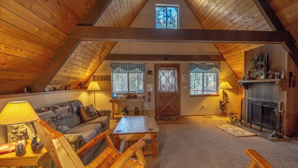 A cozy attic living room with wooden beams, a fireplace, and a loft bed. - Cozy Upper Canyon Gem w Large deck and Great Forest Views (Ruidoso)