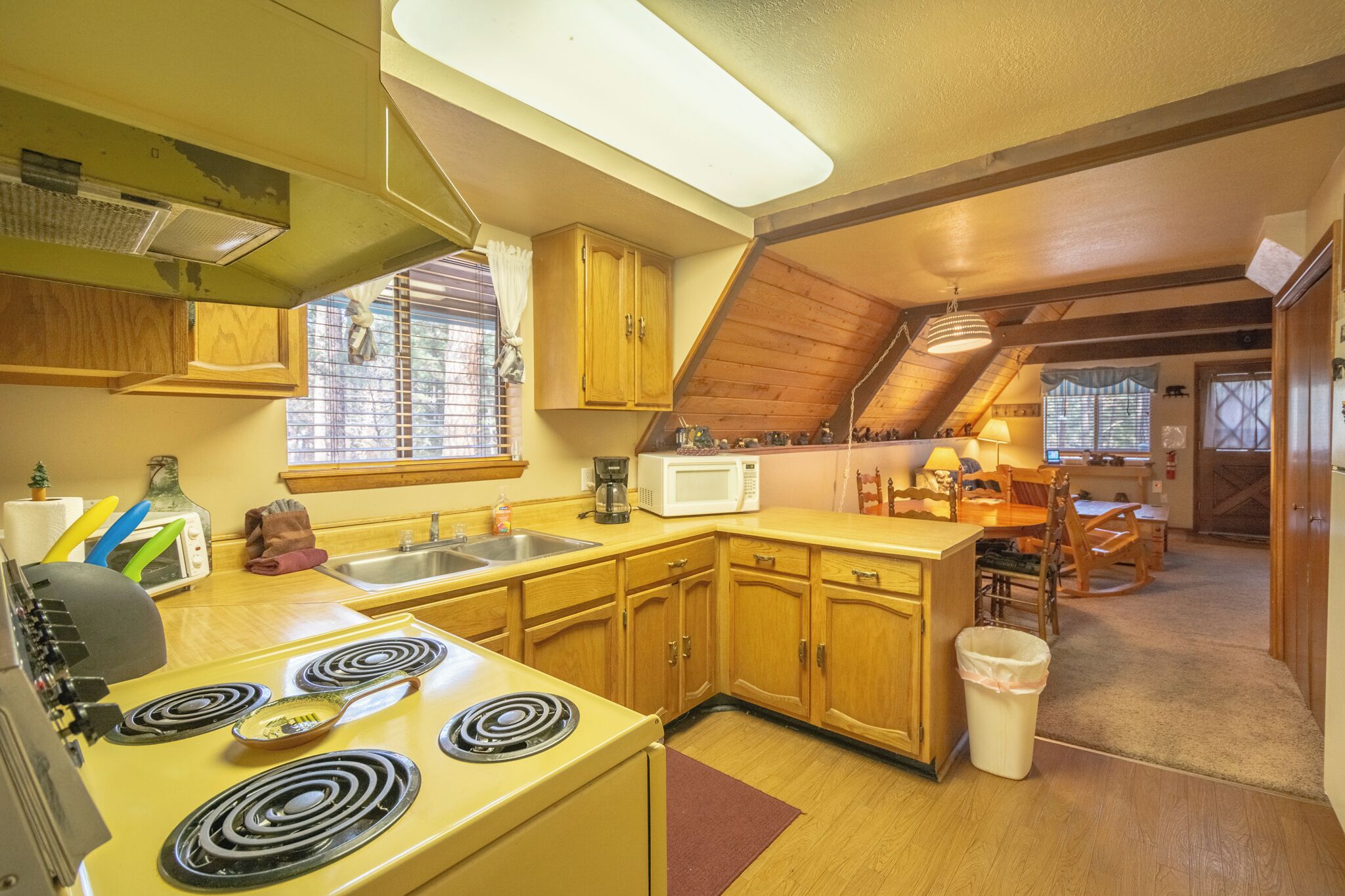 A compact kitchen with wooden cabinets, a microwave, a stove, and a sink.