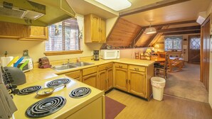 A compact kitchen with wooden cabinets, a microwave, a stove, and a sink. - Cozy Upper Canyon Gem w Large deck and Great Forest Views (Ruidoso)