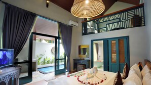 Ein Hotelzimmer mit Bett, Fernseher, Schreibtisch und Blick auf den Pool.
