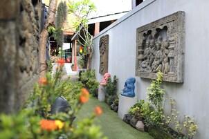 A narrow alley with a white wall featuring a relief sculpture and two statues.