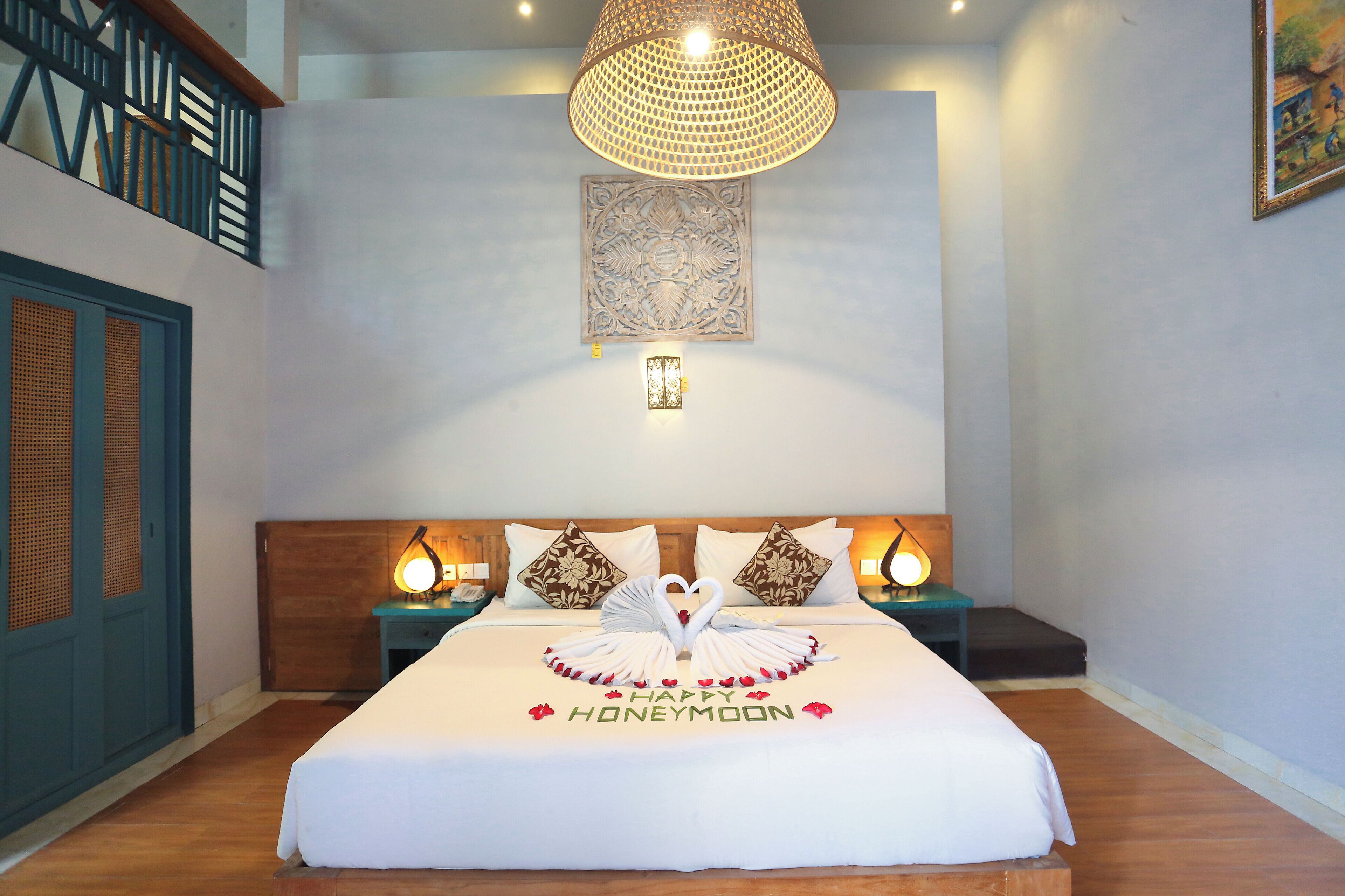 A hotel room with a bed, a decorative wall hanging, and a staircase.