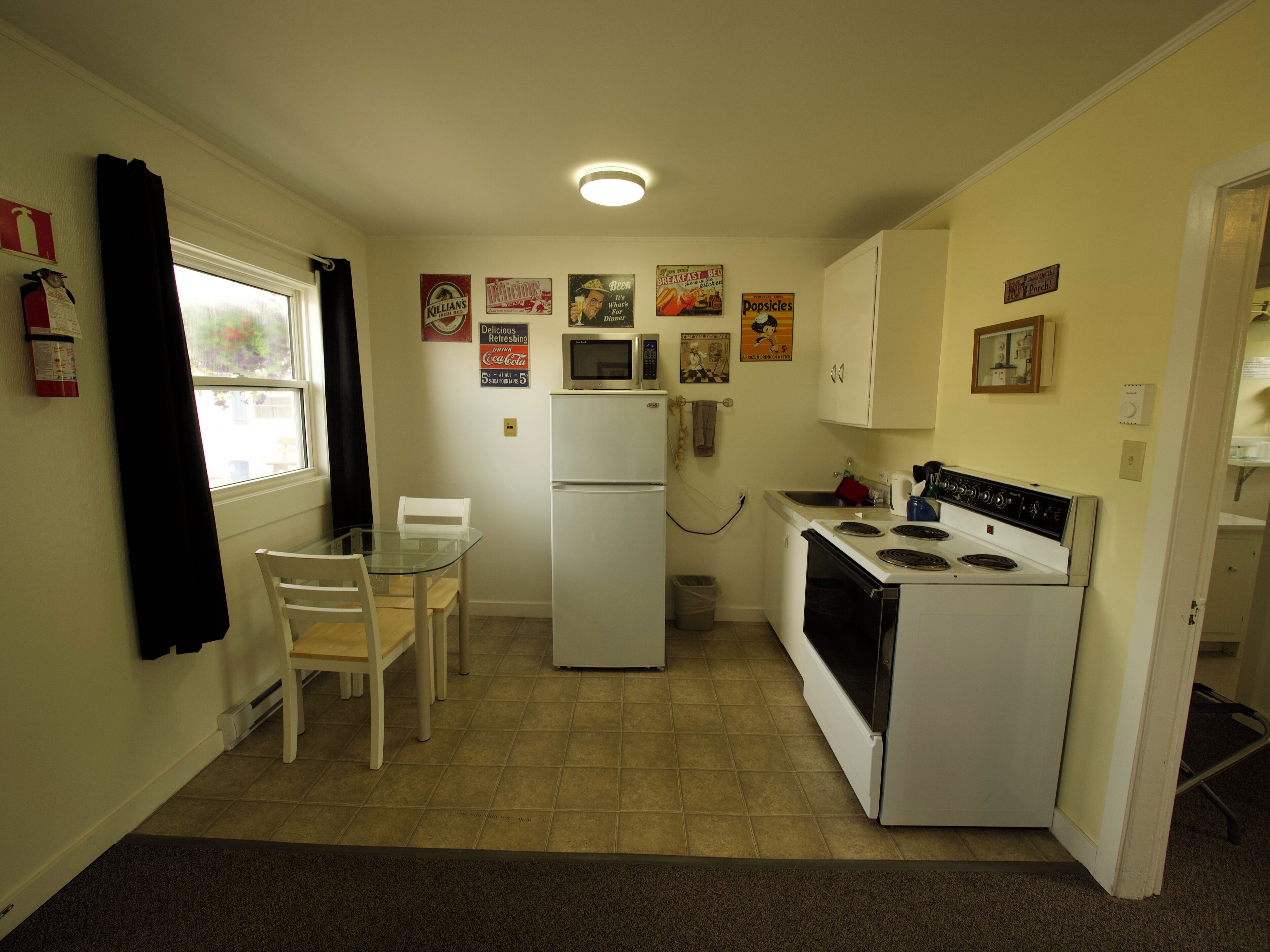 A compact kitchen with a refrigerator, microwave, stove, and a dining table with chairs.