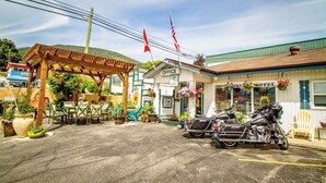 Un motel con un área de estar al aire libre cubierta, una motocicleta estacionada al frente y un letrero que indica la oficina.